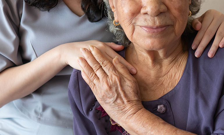 old woman holding hand of young woman