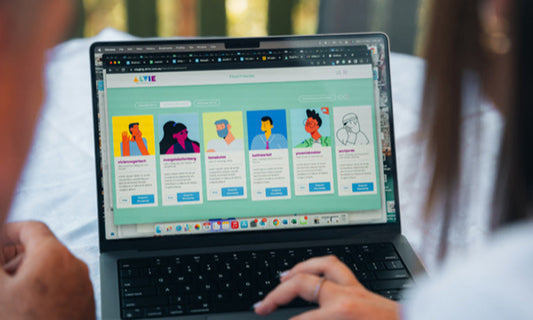 We are looking over the shoulders of two people looking at the Alvie site on a laptop