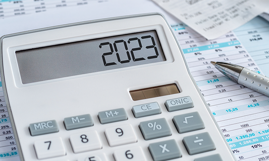 Calculator sitting on top of financial papers reading 2023