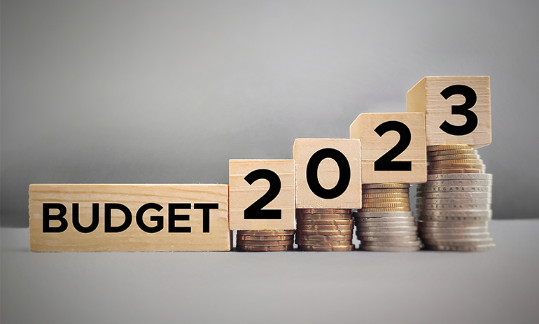 Building blocks reading Budget 2023 sitting on top of coins.