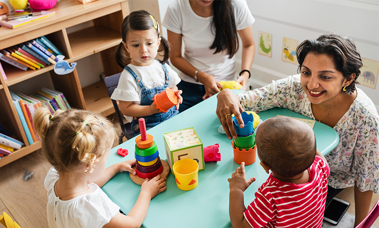 Two women playing with three young kids at a chilcare centre
