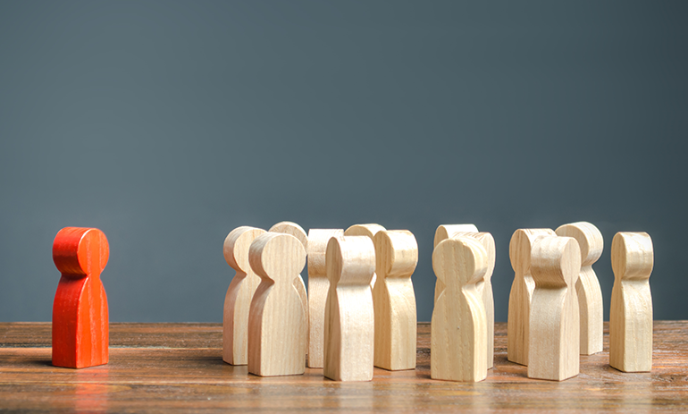Group of wooden people leaving out one.