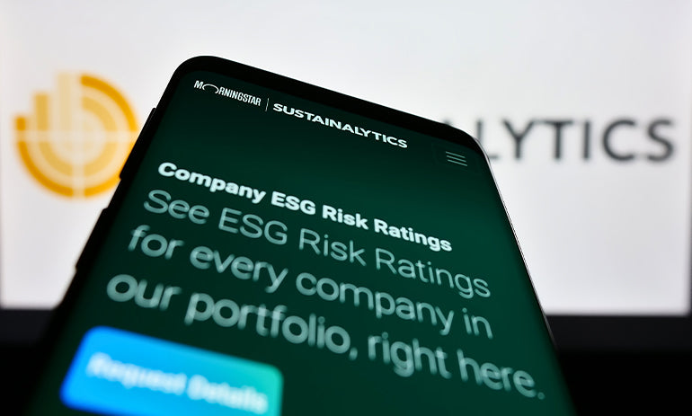 Mobile phone with website of ESG rating company Sustainalytics on screen in front of business logo.