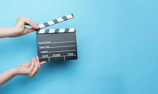 Hands holding a clapper against a blue background.