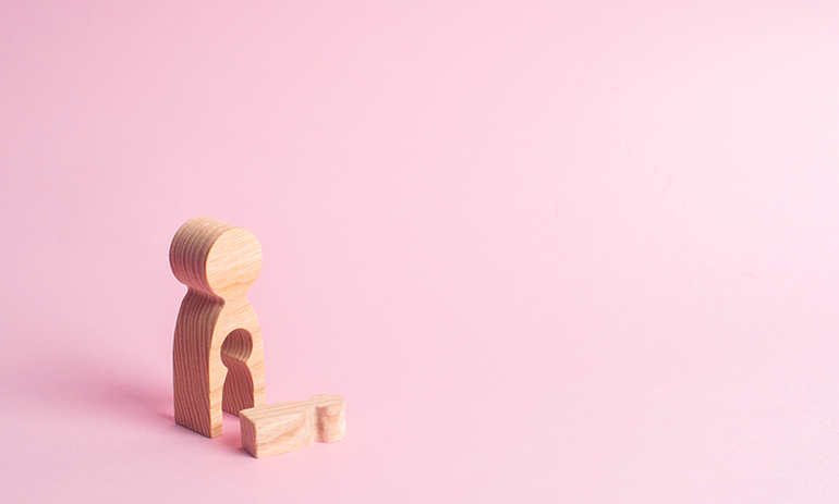 Wooden block in shape of person with a small block carved out symbolising a miscarriage.