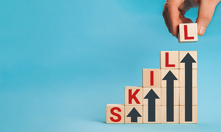 Wooden blocks reading skill underneath arrows pointing up, representing upskilling.