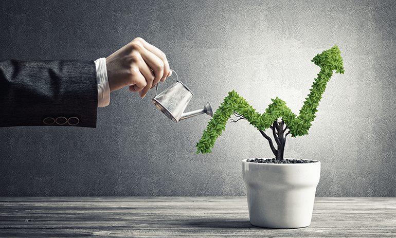 Man in a business suit watering a plant in the shape of an upward arrow.