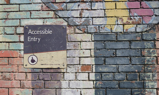 A colourful brick wall with a sign on it that says 'accessible entry'.
