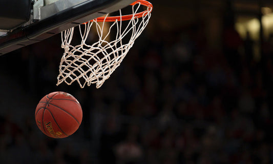 A basketball falling from a hoop it has just gone through.