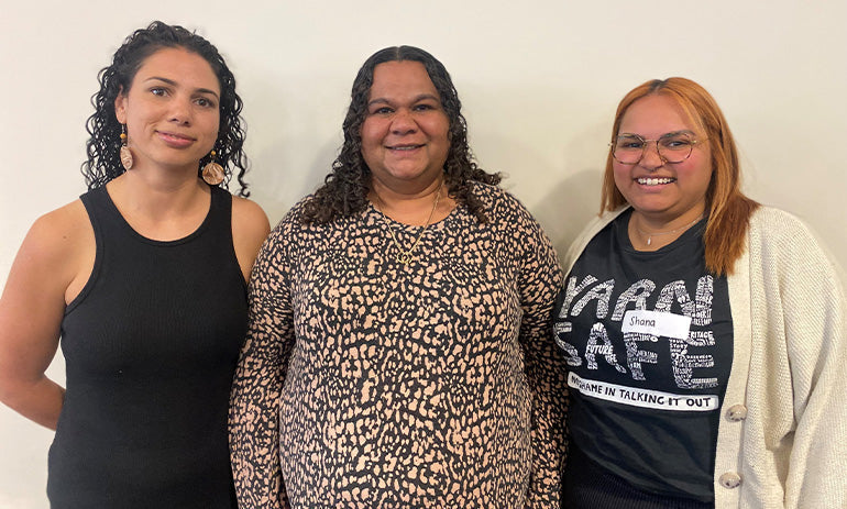 Three Aborginal women smile at the camera. On the left is Eileen, in the middle is Ricache and on the right is Sharna.