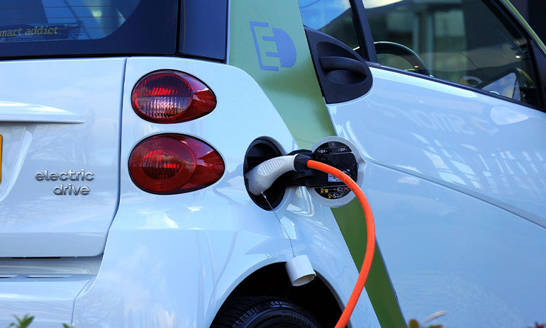 A white electric car plugged into a charger.