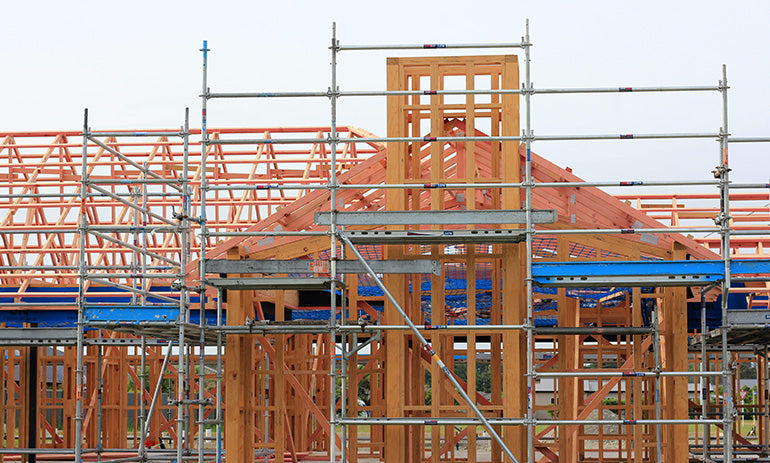 A house under construction. We can see the wooden frame and the scaffolding around it.
