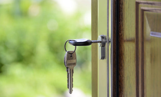 A key in the lock of a brown wooden door.