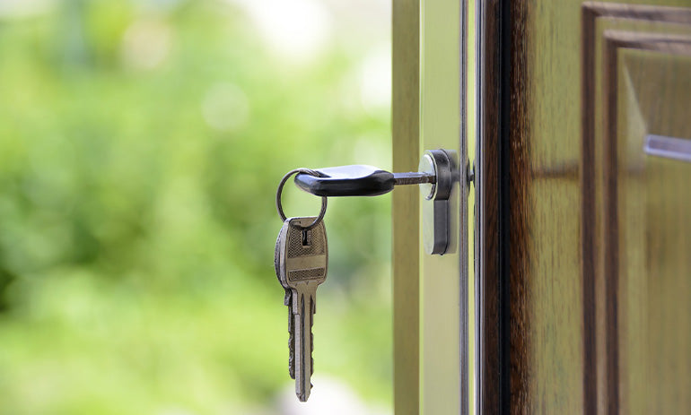 A key in the lock of a brown wooden door.