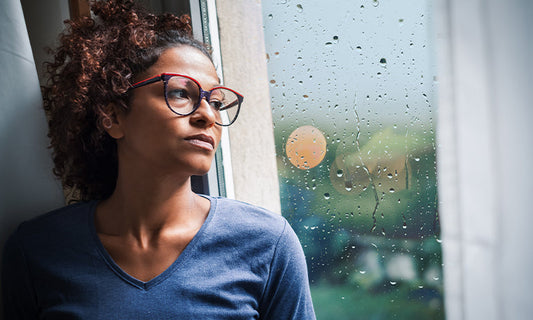 woman looking out of a window at the rain