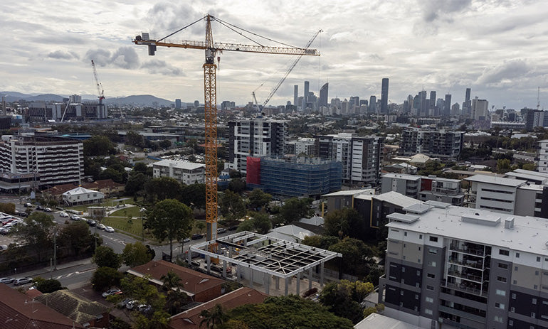 A crane constructs a building in a crowded city.
