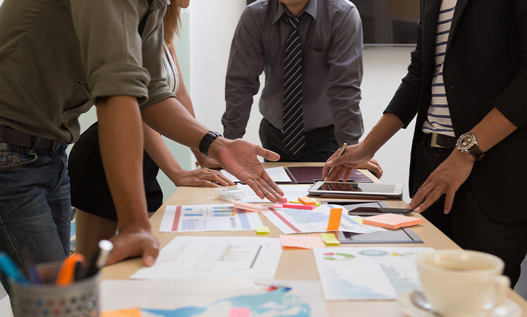 group of people standing around a table working together