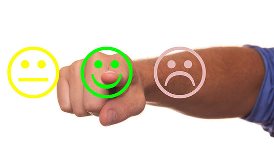 We can see a make arm reaching towards the screen. There are three faces on the screen, a yellow one that has a bland expression, a green smiley face and a red unhappy face.