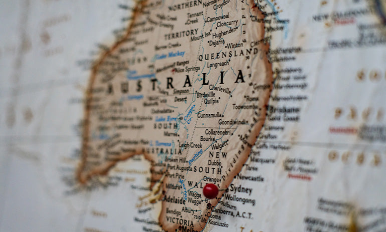 An old fashioned looking brown map of Australia with a pin stuck somewhere around Sydney.