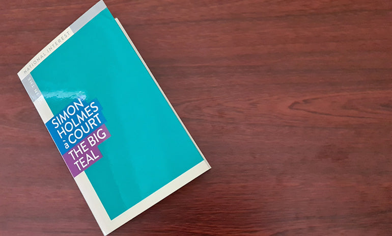 A small blue book lies on a desk. It is title The Big Teal.