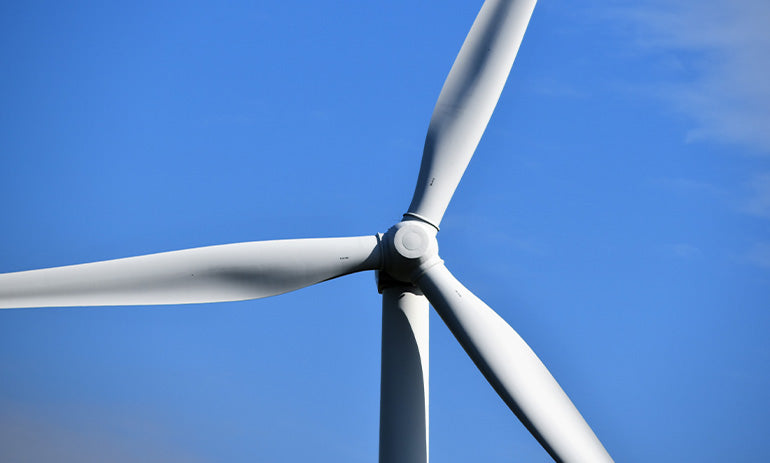 A white wind turbine against a blue sky.