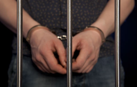 youth hands in cuffs behind bars RS