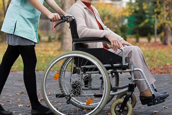 Care worker pushes a lady in a wheelchair