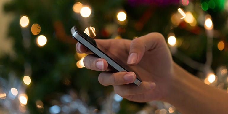 person on their mobile in front of Christmas tree