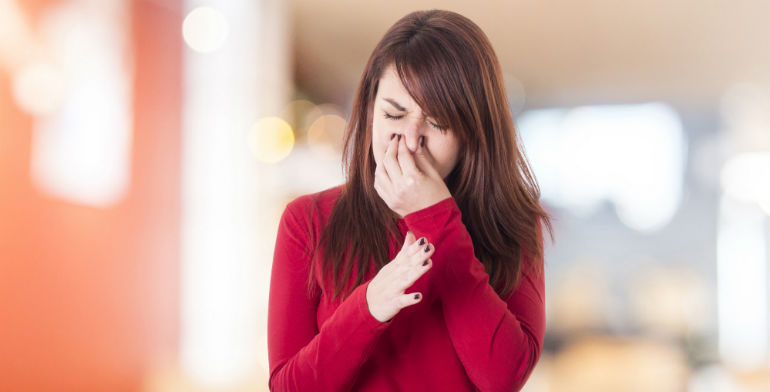 Woman holding her nose because of a bad smell