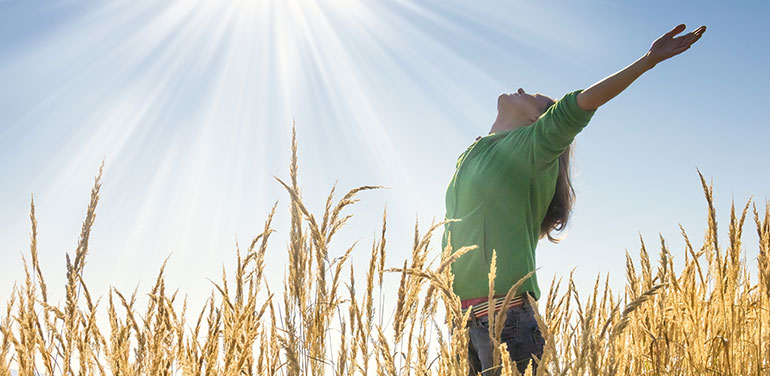 woman with outstretched arms in a cornfield