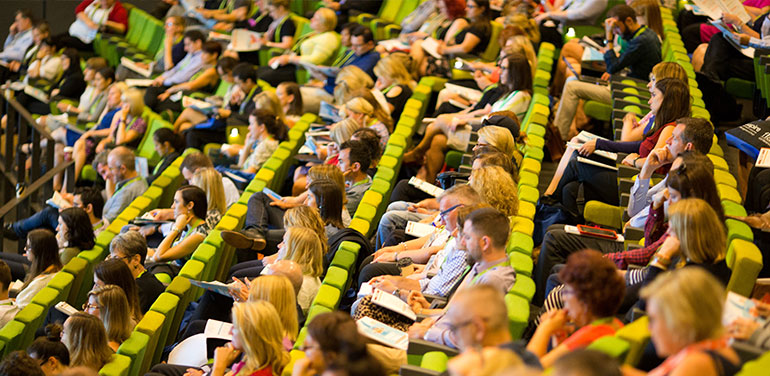 People attending a conference sitting in a lecture hall