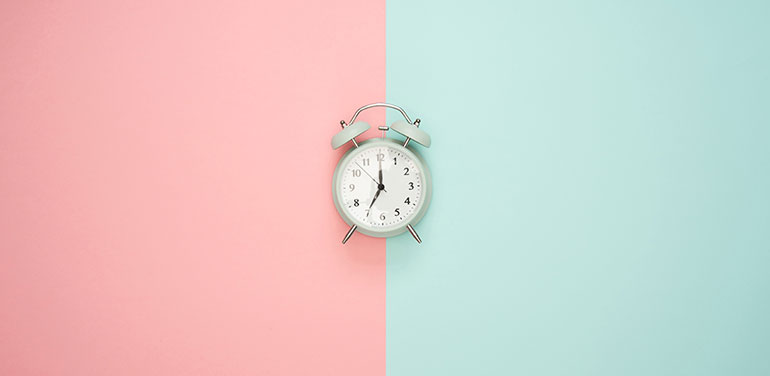 alarm clock on pink and blue background