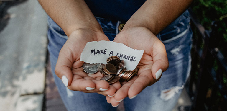 hands holding coins and a piece of paper saying 'make a change'