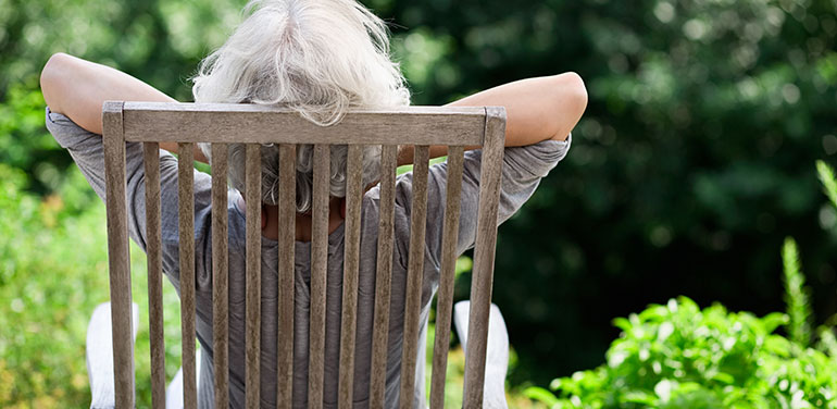 Retired woman with her back to the camera relaxing in a chair outside