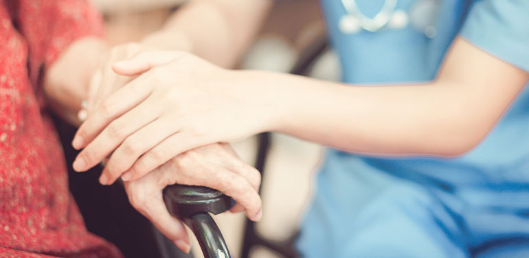 nurses hand comforting woman in wheelchair