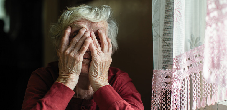 older woman with hands covering her face