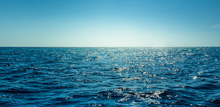 Blue ocean panorama with sun reflection