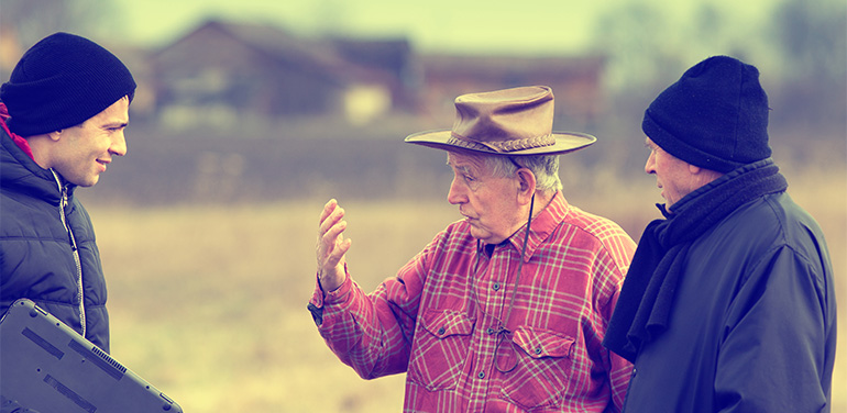 two men talking to a farmer on his land