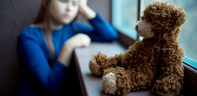 teddy bear sitting in the window, a girl blurred in the background