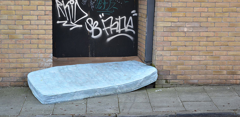 mattress on floor in front of a graffitied doorway