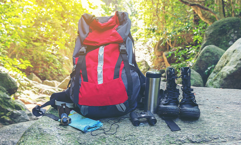 backpack and walking boots on a rock in a forest