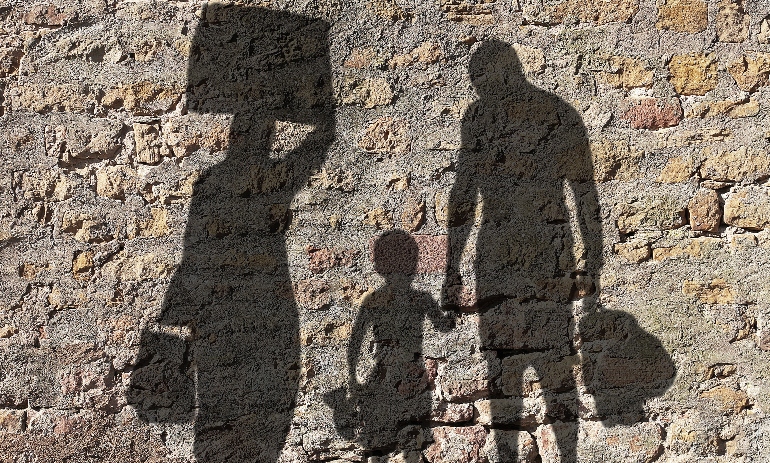 Refugee family shadow against a brick wall