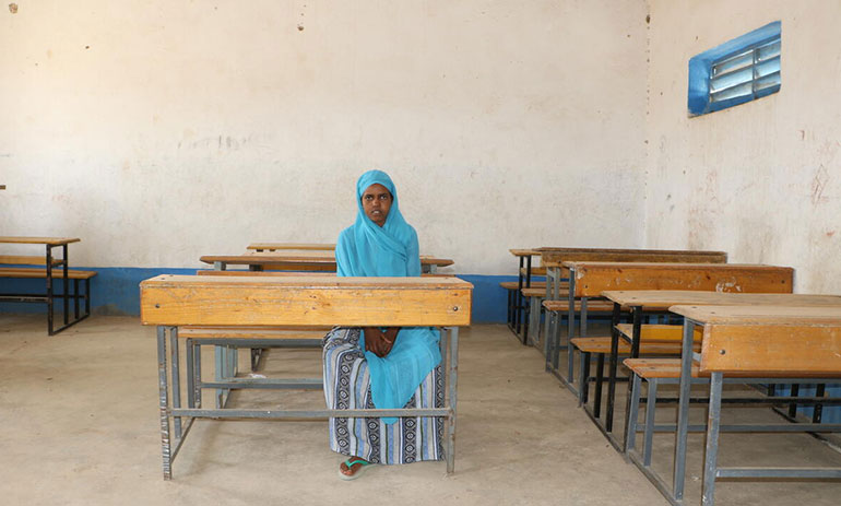 Young girl, Aisha, sitting alone in a classroom in Ethiopia.