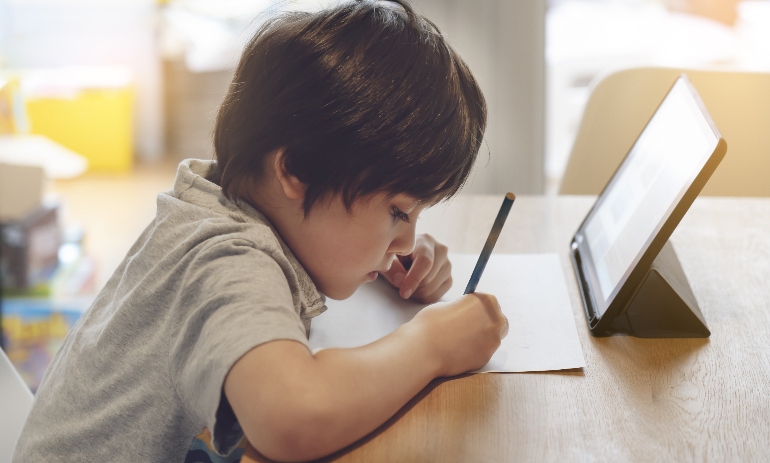 Portrait of preschool kid using tablet for his homework