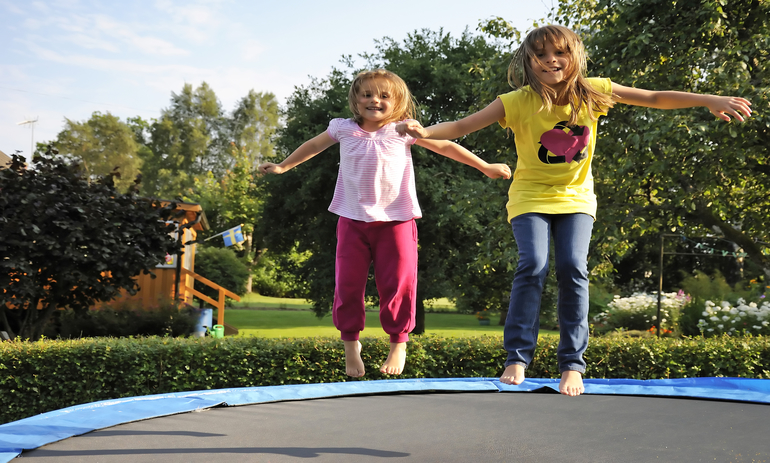 Two girls jumping on a trampoline