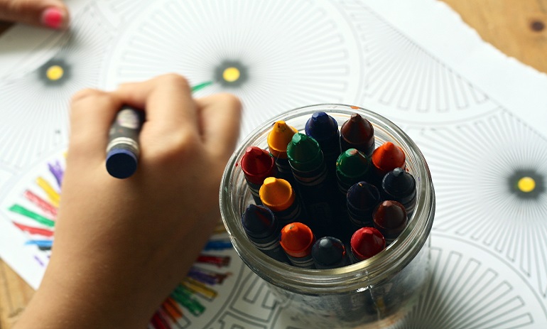 close up of child colouring in with crayons