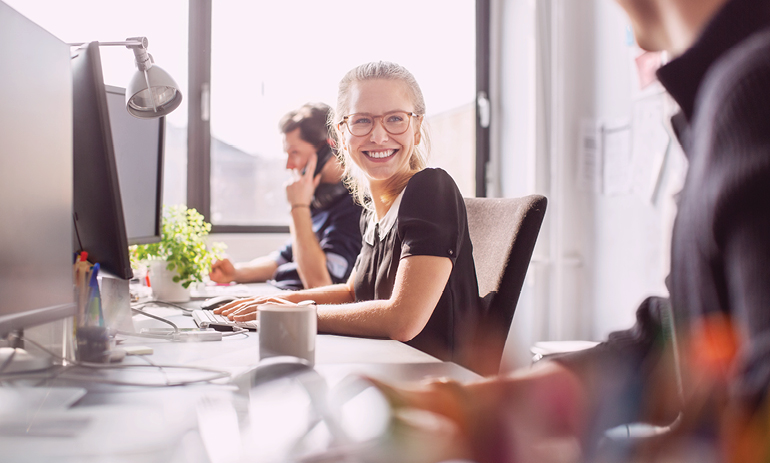 Woman at her desk smiling at a colleague