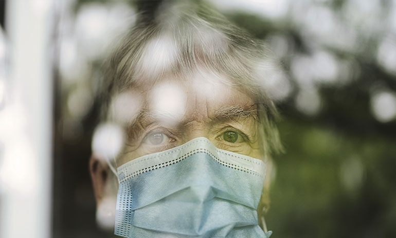 older woman wearing a face mask looking through a window