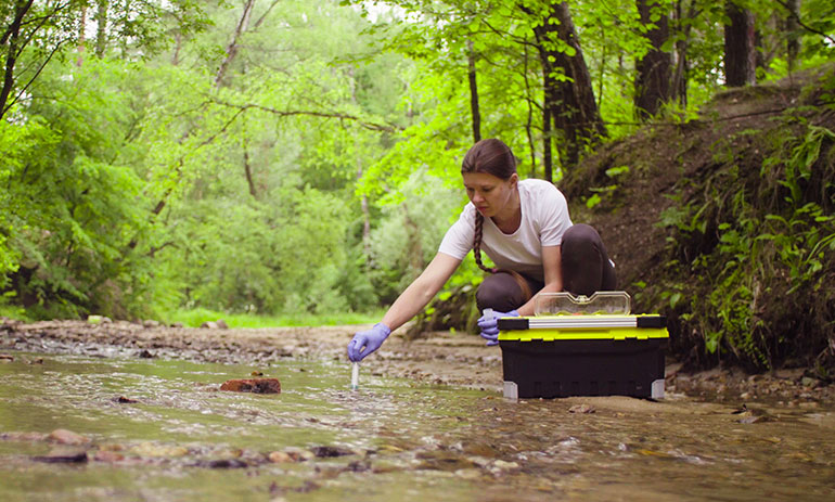 femal environmental scientist testing water in a creek