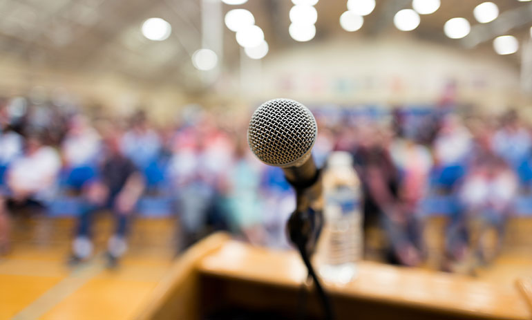 close up on microphone with blurry background with people in a hall